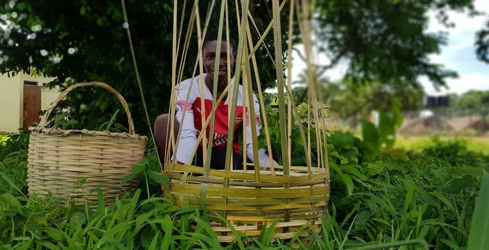 A young boy sits behind a almost completed basket