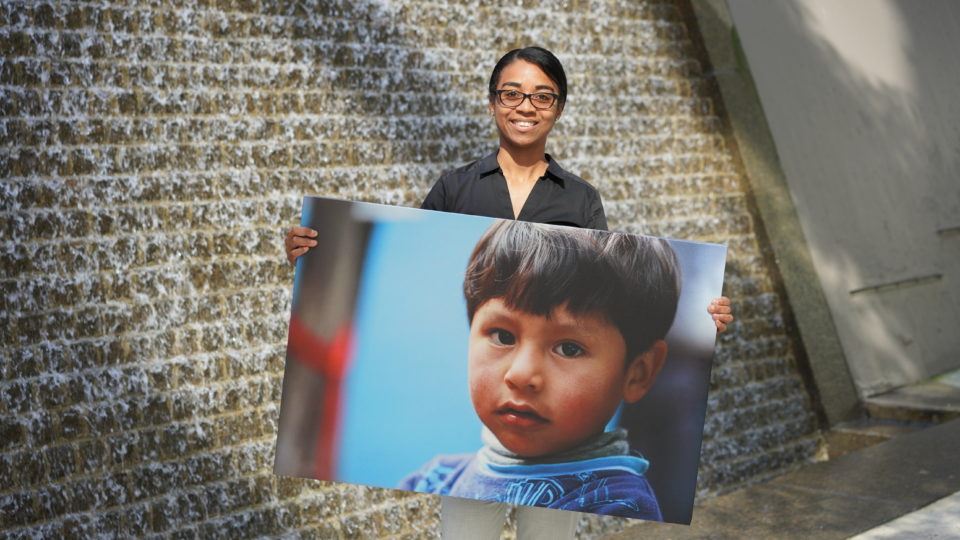 Carolina poses with an image of a child served in the field