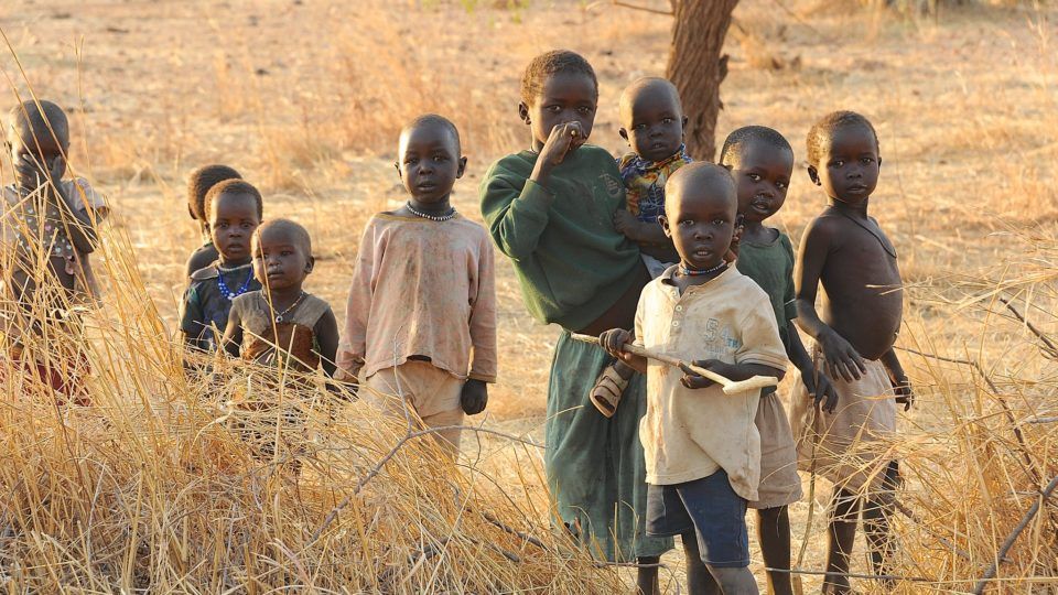Children stand together in a group outside. They live in the Nuba Mountains