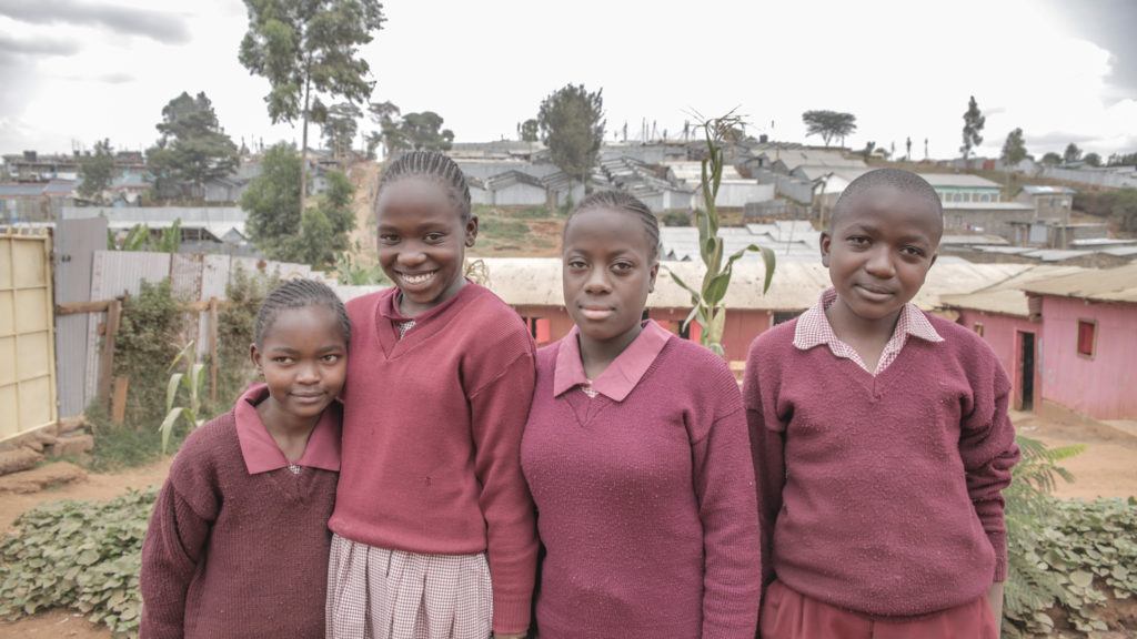 Dreams students stand together outside of their school. They have mentors who guide them. 