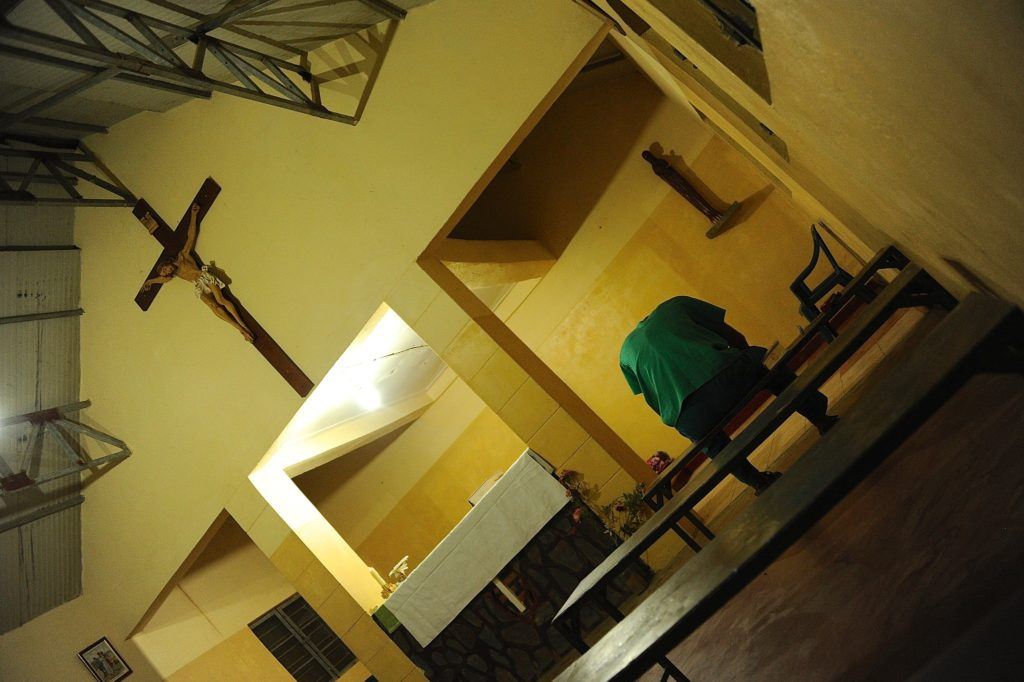 Dr. Tom sits with his head down praying in a church