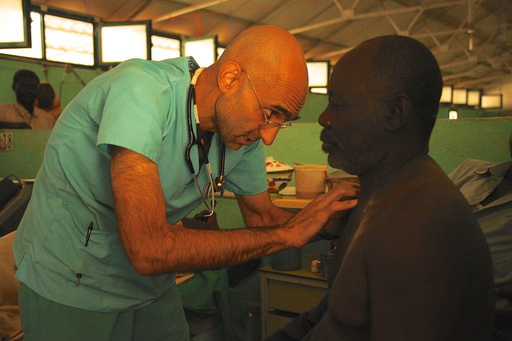 Dr. Tom leans over a patient to treat him.