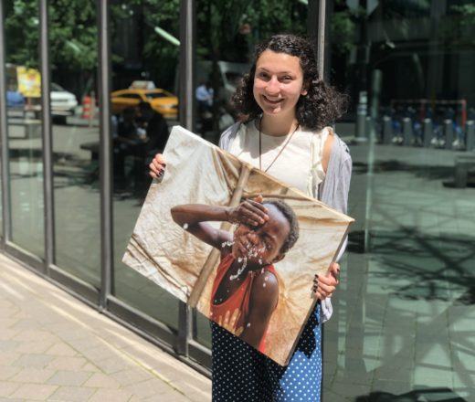 CMMB intern Grace holds a canvas image of a child CMMB serves in the field