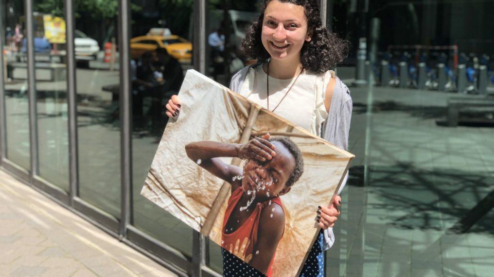 CMMB intern Grace holds a canvas image of a child CMMB serves in the field