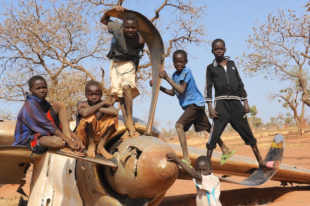 Nuba children standing on a crashed plane