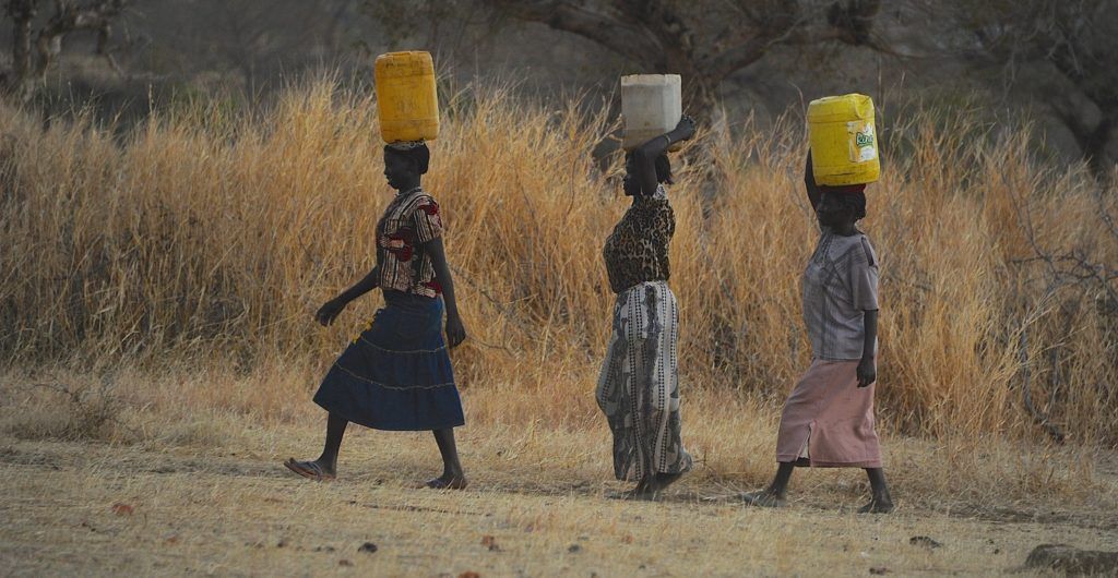 Nuba women carrying water on their heads