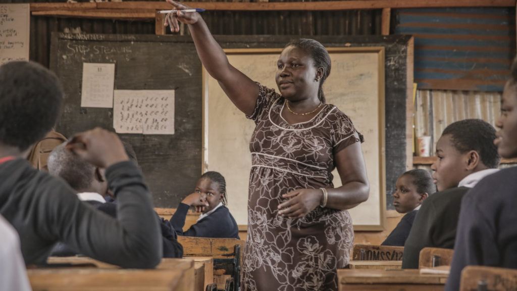 Sarah, a patron of the dreams program stands in front of her class of students teaching. She is a mentor for students