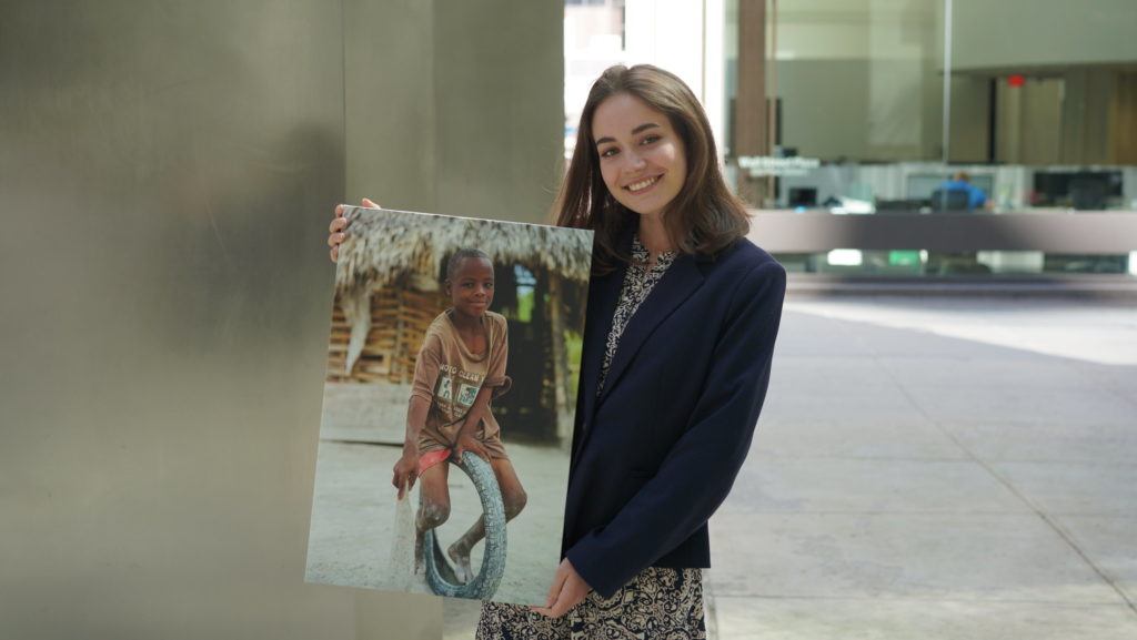 Sophia posing outside with a canvas photo of an individual we serve 