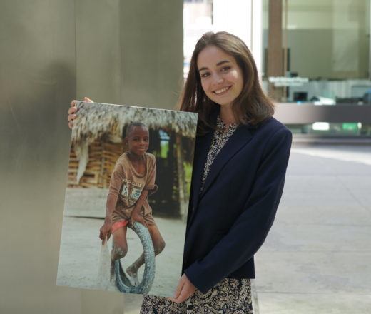 Sophia is a CMMB Intern, in this photo she poses outside with an image of a child we serve in the field