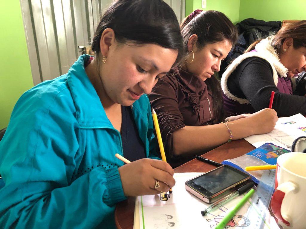 A mother in Peru sits in English Class. She participates by completing a worksheet independently