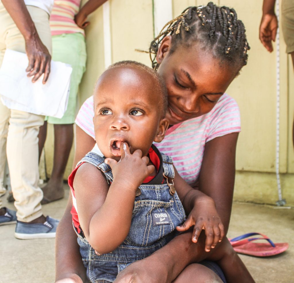 A mother sits with her child in the DR. she lives on the Bateyes and accesses medical aid for her son when the mobile clinic comes. 