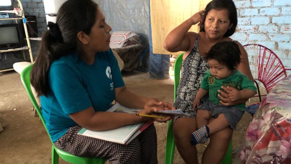 Diana sits with a community member in Peru