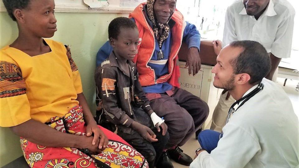 Dr. Jose kneeling in front of patients