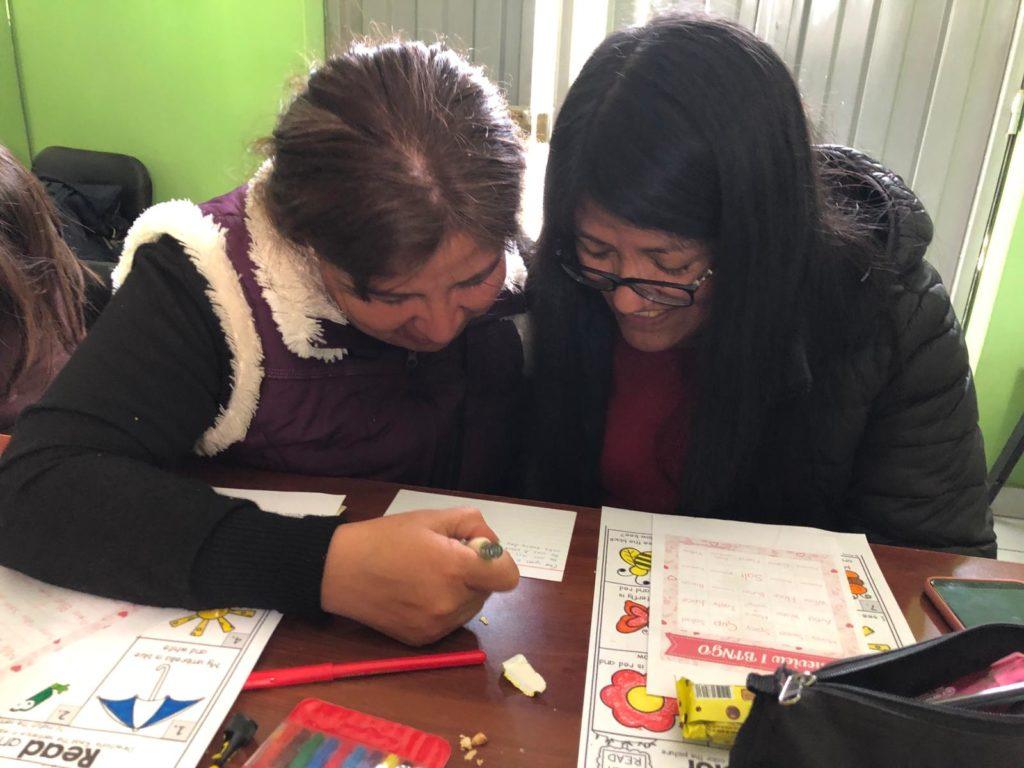 Two women look over books together in English Class