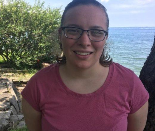 Abigail is a CMMB volunteer. She stands in front of an ocean