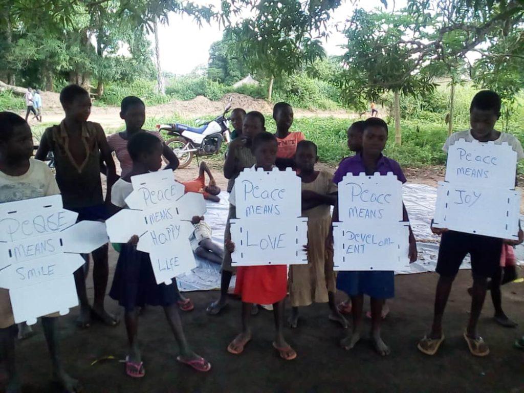 Children hold white paper sharing what peace means to them
