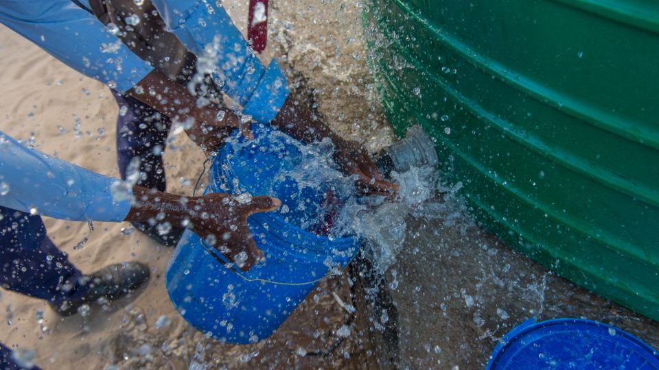 Children collect water from. It is spraying around the bucket