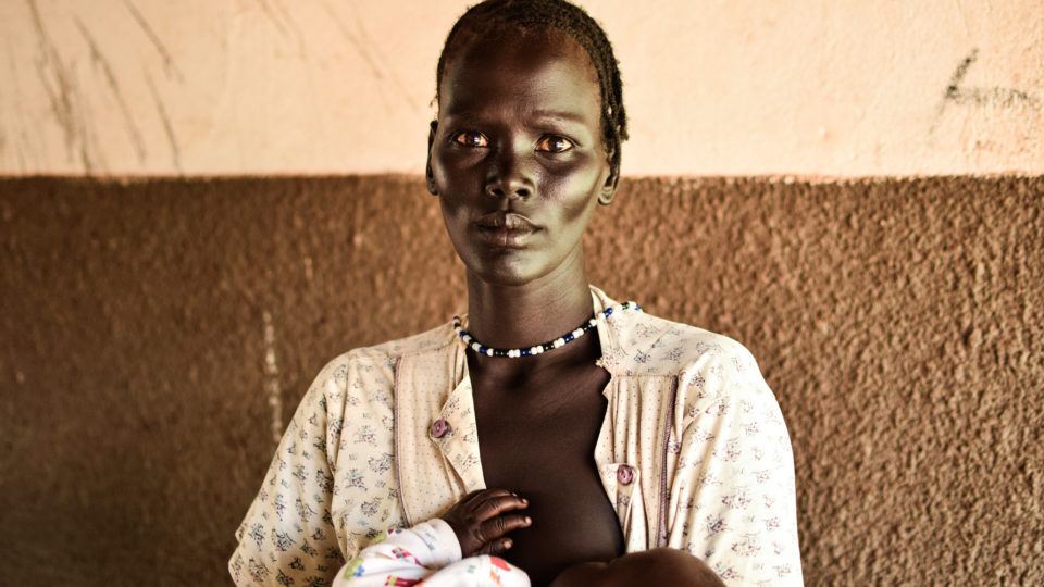 Dinka woman with very beautiful black skin breastfeeding her baby in South Sudan.