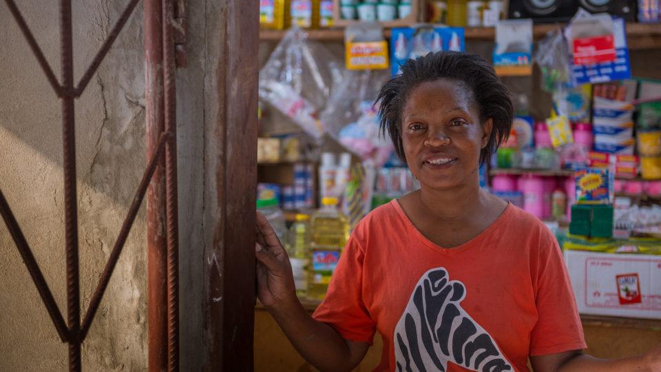 Pamela stands at her store front. She wears a shirt with a zebra on it.