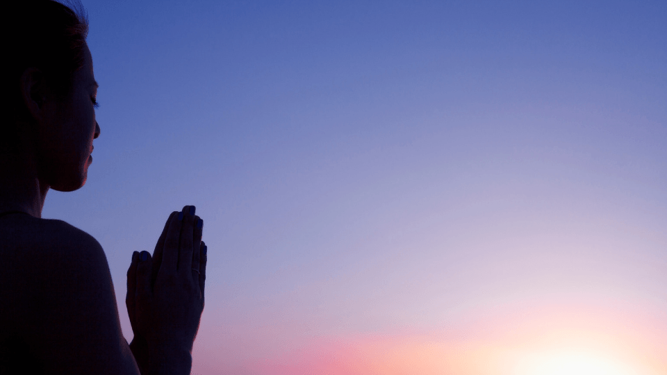 woman praying in the sunset