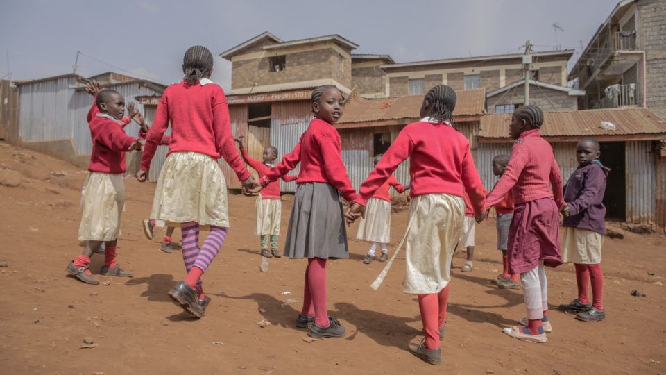 children holding hands in a circle in kenya