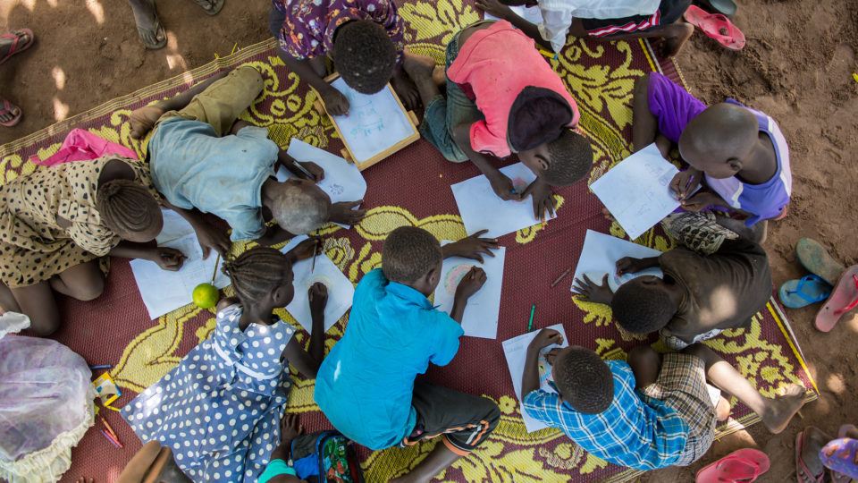 children drawing together on a blanket