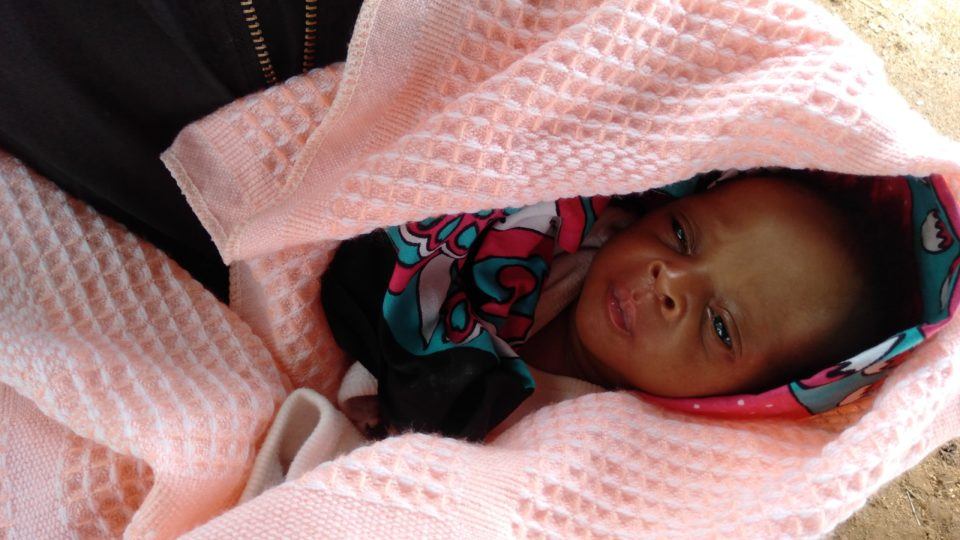 Baby Joshua swaddled in a blanket in his grandmothers arms