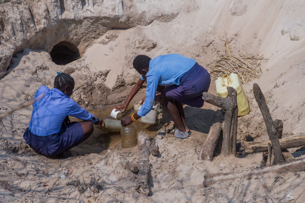 girls collecting water in well zambia