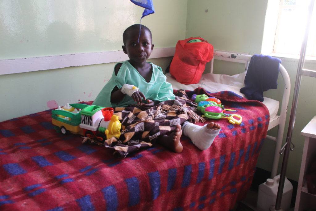 a child sits on a bed at the mutomo mission hospital in Kenya
