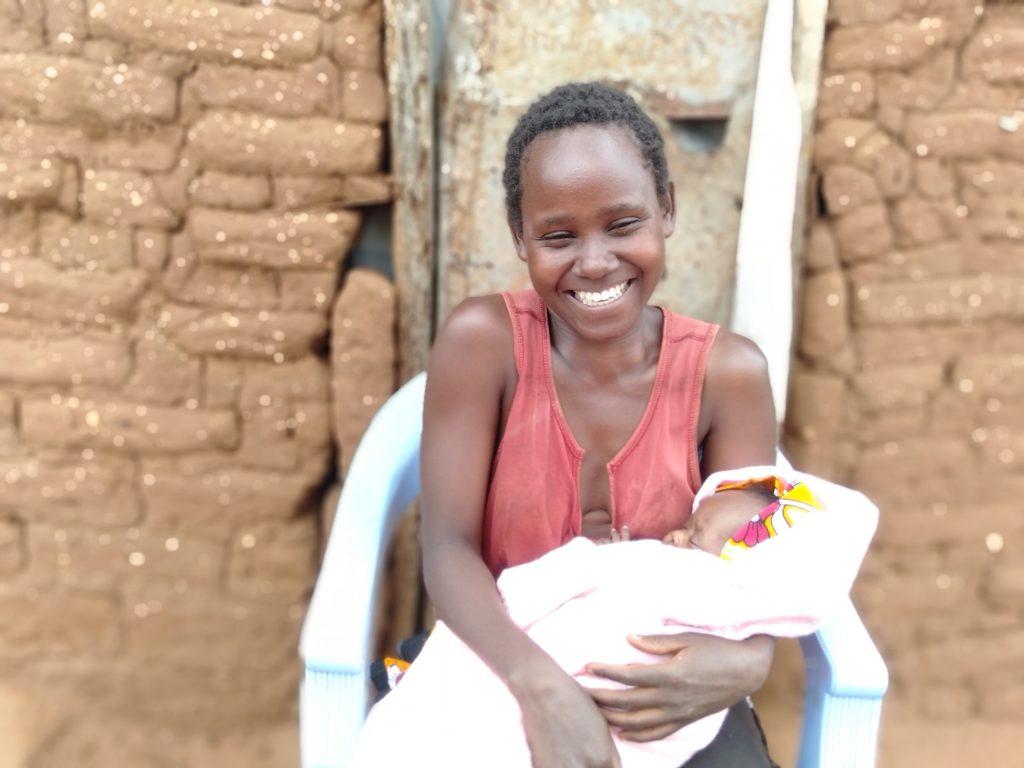 A mother smiles holding her baby 