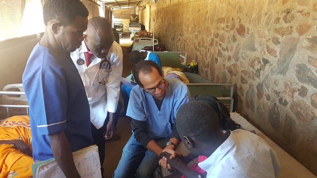 Dr. Jose sits beside a patient