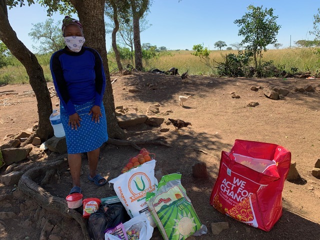 Woman stands wearing mask next to donated food to keep people home during Covid-10