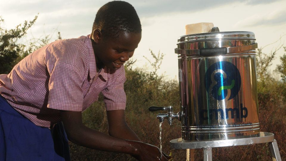 Anastasia washing hands in Kenya with clean water from CMMB-provided water dispenser.