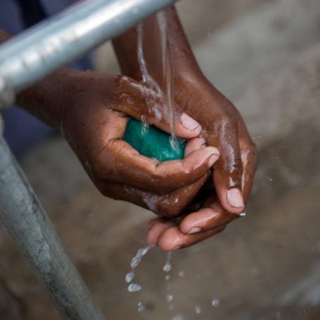 Hands-Holding-Soap-Under-Faucet-Running-Clean-Water Hands Holding Soap Under Faucet Running Clean Water