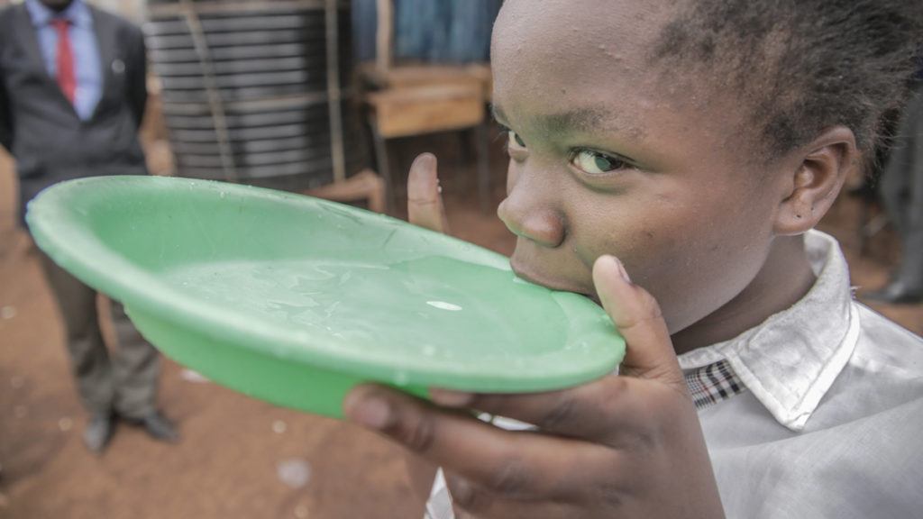 Young Girl Drinking Clean Water from Green Container in Kenya in 2017