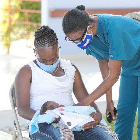 Community healthcare worker at Bishop Joseph Sullivan Hospital with mother and child in Haiti in July 2020.