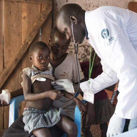 A doctor checks the temperature of a child sitting on mother's lap in internally displaced persons camp in Rimenze, South Sudan in December 2017.