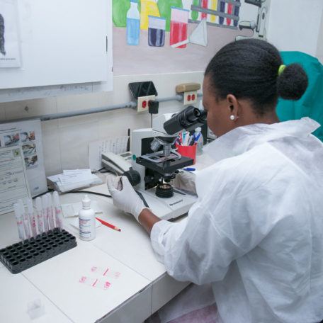 A lab techinican reviews samples under a microscope in Haiti in Augsut 2019