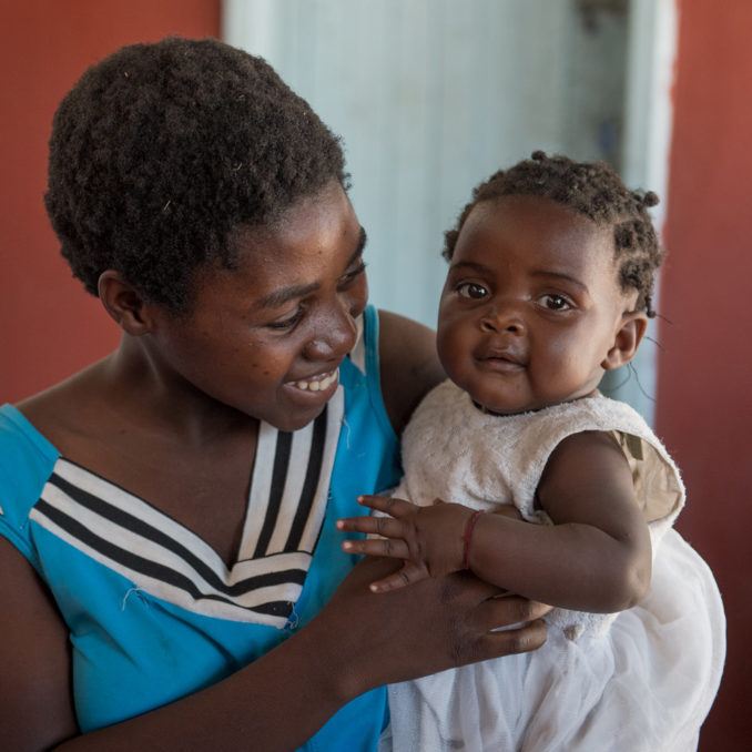 Mother holds her smiling daughter in Mwandi, Zambia in October 2019.