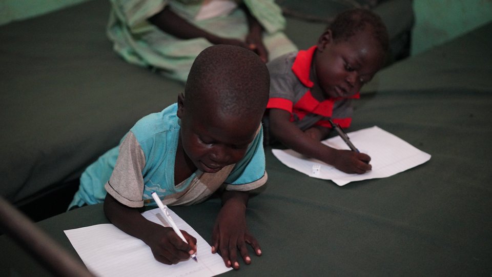 Two children writing who are being treated for malnutrition at Mother of Mercy Hospital in Sudan in June 2018.