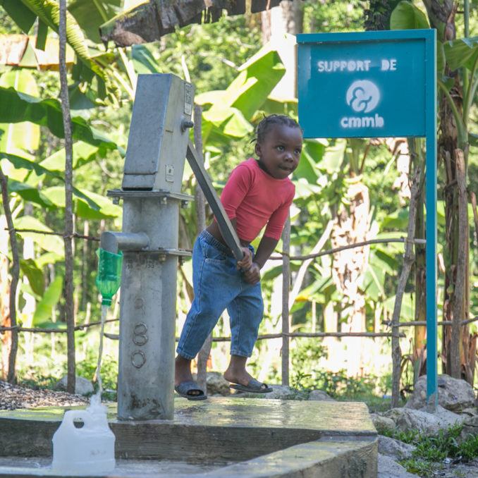 A girl collecting clean water from a well in Haiti in July 2020.