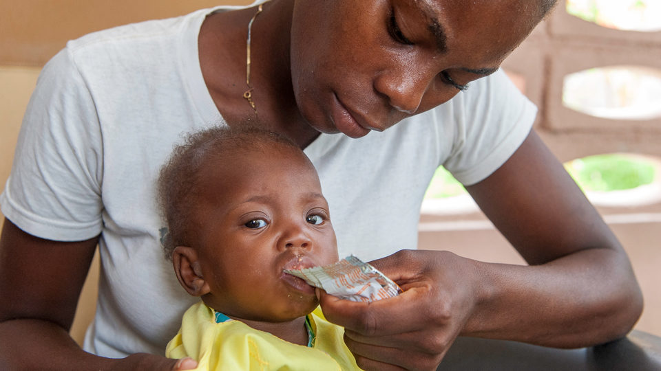 A mother feeding her child nutritional Plumpy'Nut in Cotes de Fer, Haiti in July 2018.