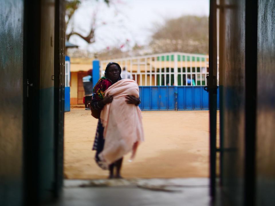 A mother holding her child walks into the Mutmo Mission Hospital in Kenya in 2018