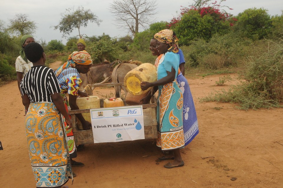 Women carry purified water, made possible by CMMB's partnership with CMMB, in Kenya in June 2020