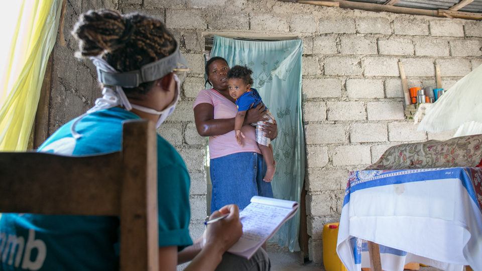 A community health worker with a mother and child during COVID-19 response in Haiti in July 2020.