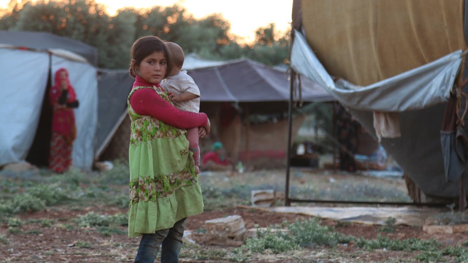 A young girl holding a baby in a refugee camp in northwest Syria in June 2019.