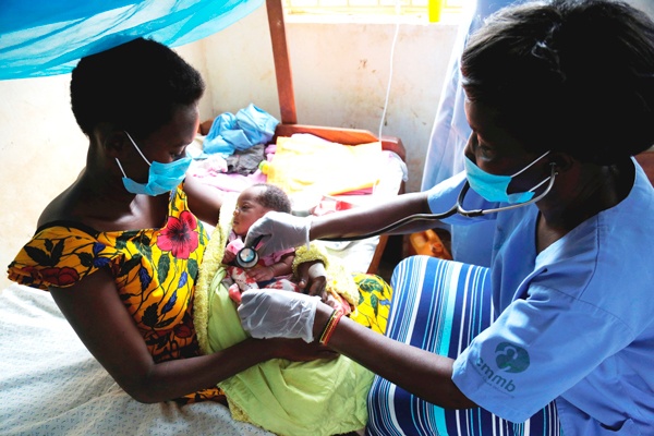 A mother and her infant with a heatlhcare worker after delivery.