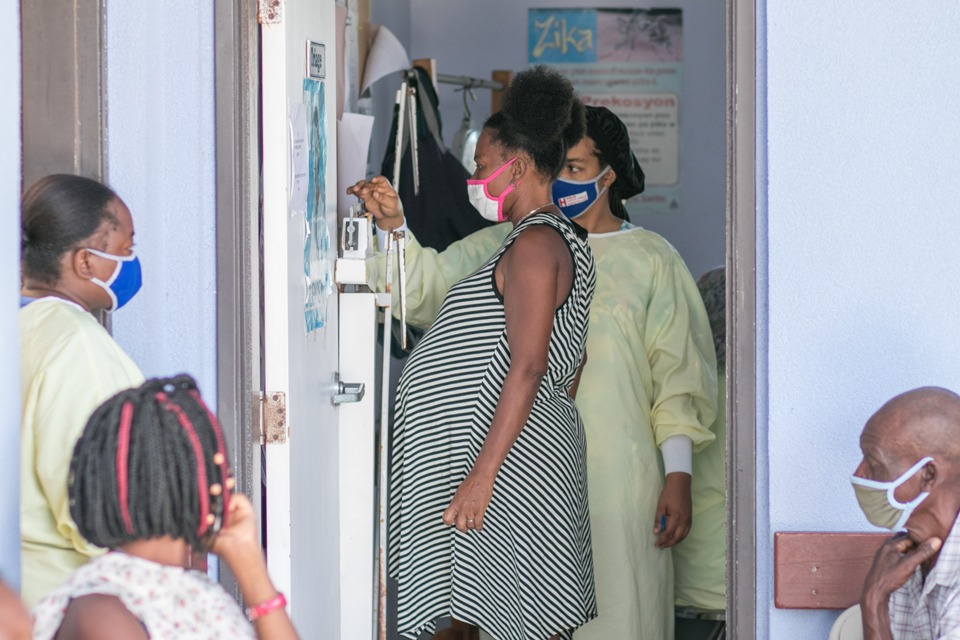 A pregnant woman being weighed on a scale by a healthcare worker at Bishop Joseph Sullivan Cetner for Health hospital in Cotes de Fer, Haiti in July 2020.