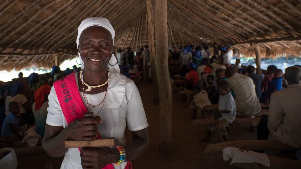 A woman smiling with a cross during churhc service in South Sudan in October 2018.