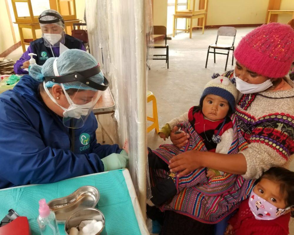 A community health worker providing care to a mother and her children during COVID-19 in Peru.
